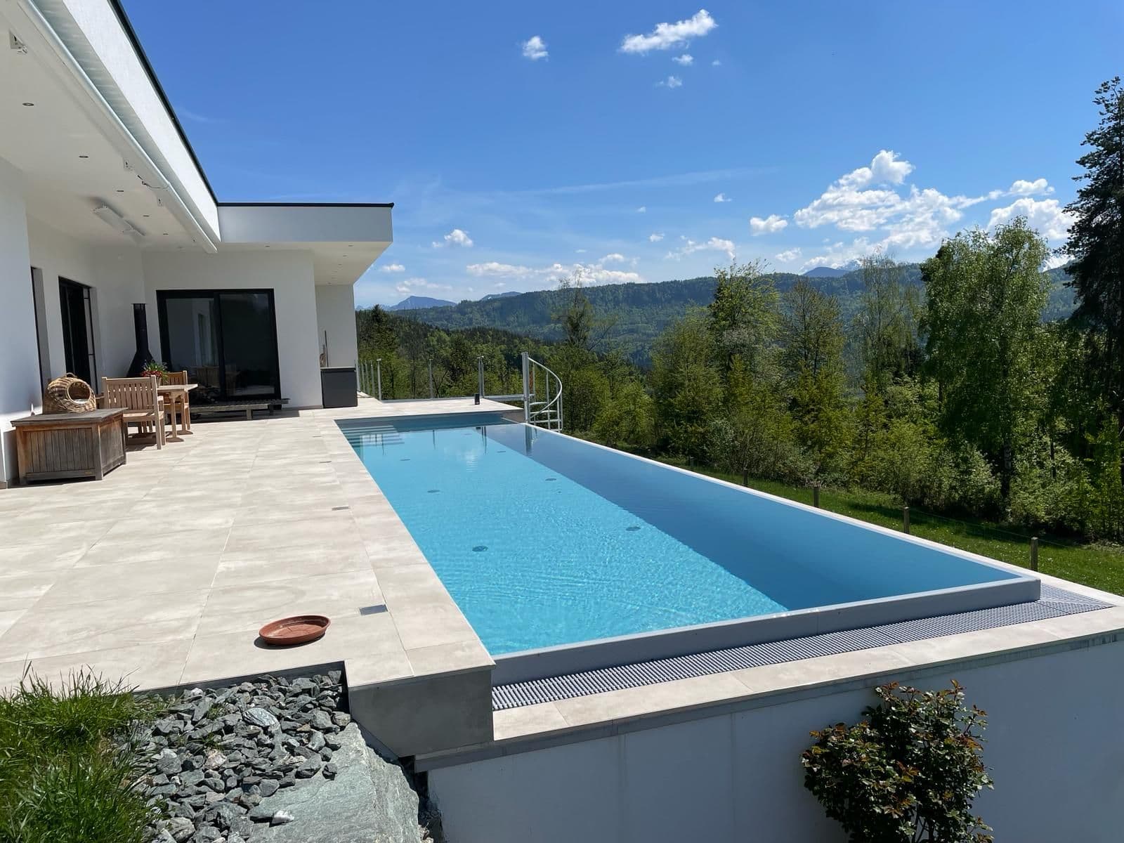 Infinity-Pool auf der Terrasse eines modernen Hauses mit Blick in die Landschaft